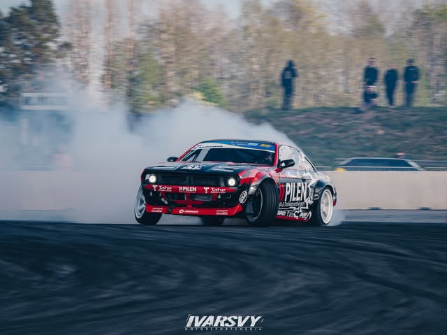 Pilen, en röd och svart Nissan S14, i full sladd med rök från bakdäcken